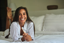 Smiling girl lying on a bed with a BAMWOO bamboo toothbrush in her hand