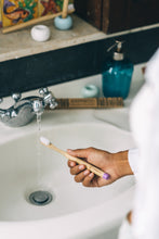 Brushing teeth with a purple BAMWOO bamboo toothbrush