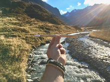A BAMWOO bamboo toothbrush held up in front of a glacier meltwater stream in the Austrian Alps