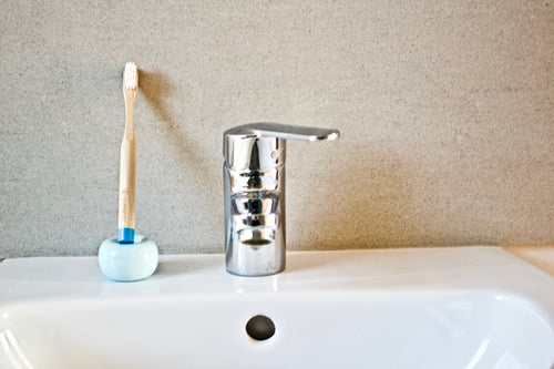 Children's bamboo toothbrush in ocean blue from BAMWOO on sink in bathroom