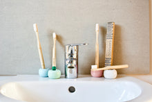 BAMWOO's children's and adult bamboo toothbrushes on the sink in a bathroom