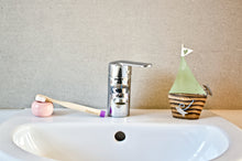 Children's bamboo toothbrush in dawn purple from BAMWOO on sink in bathroom