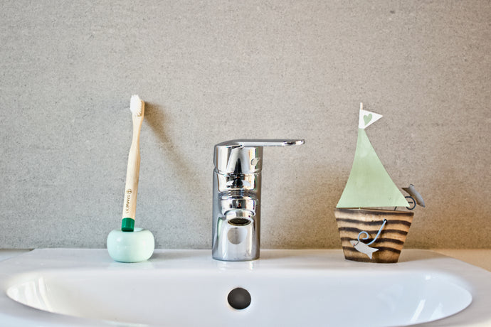 Children's bamboo toothbrush in forest green from BAMWOO on sink in bathroom